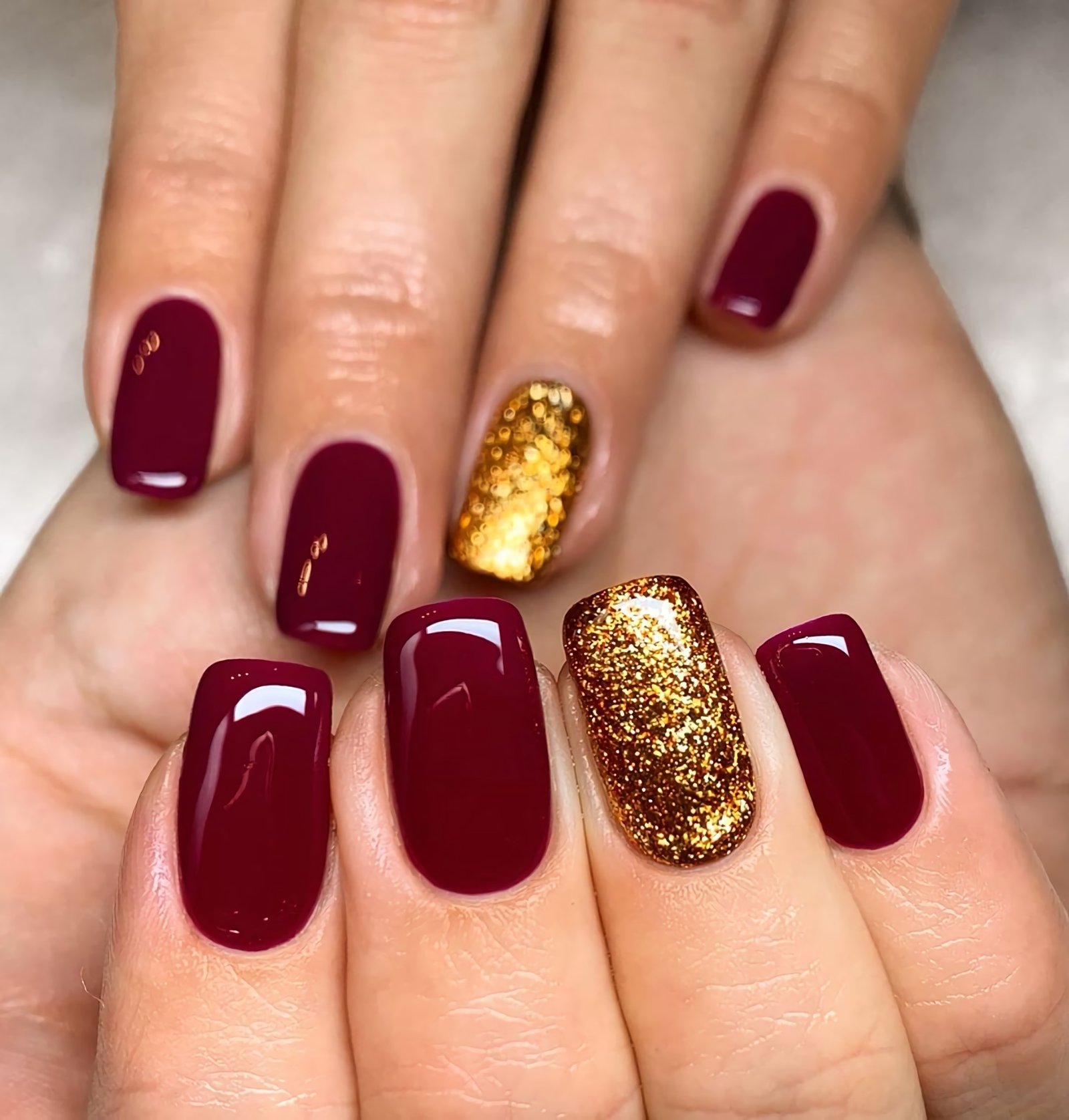 burgundy manicure with accented gold nail